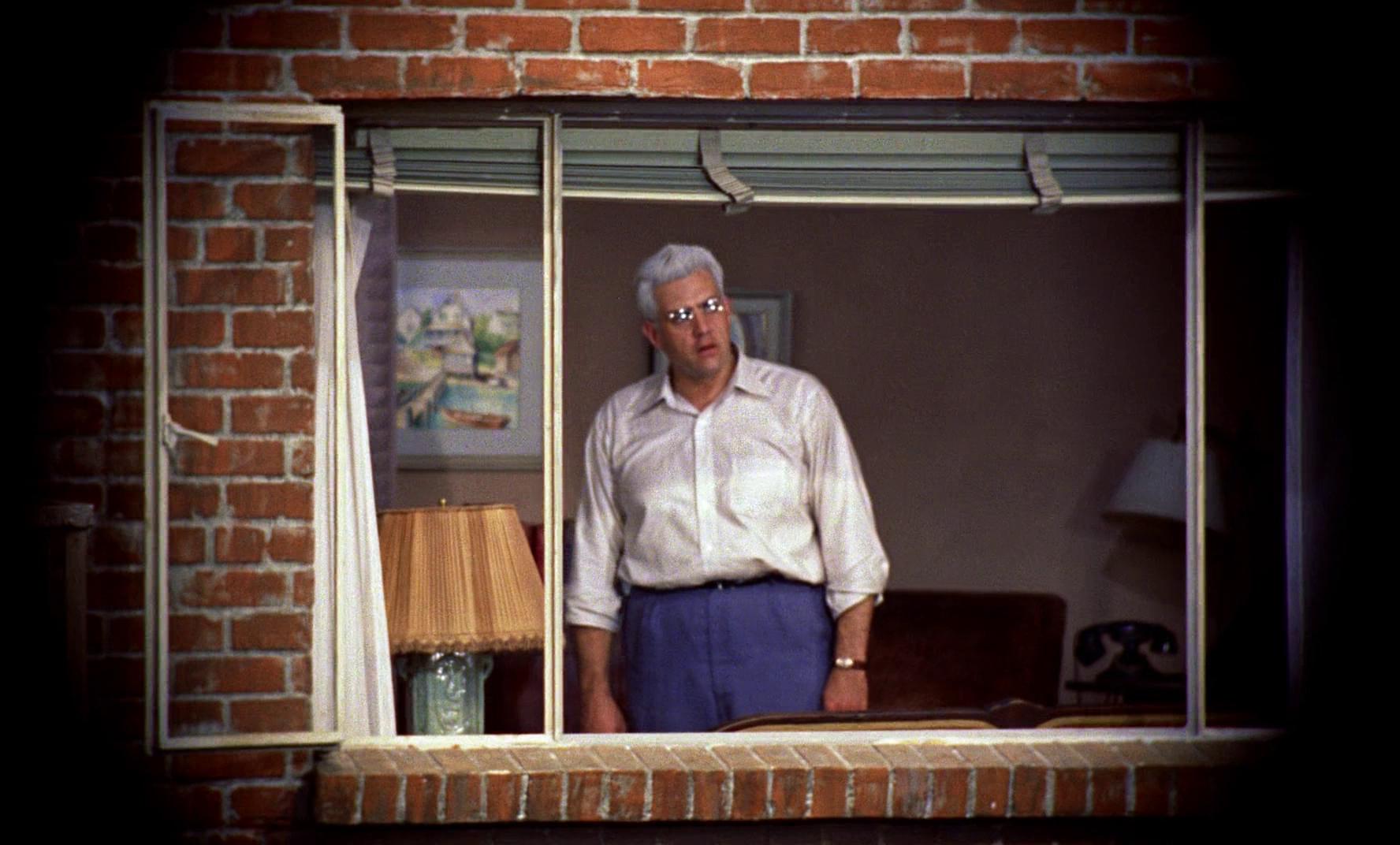 Thornwald à sa fenêtre, tel que vu par Jeff, qui l'observe à travers l'objectif de son appareil photo.